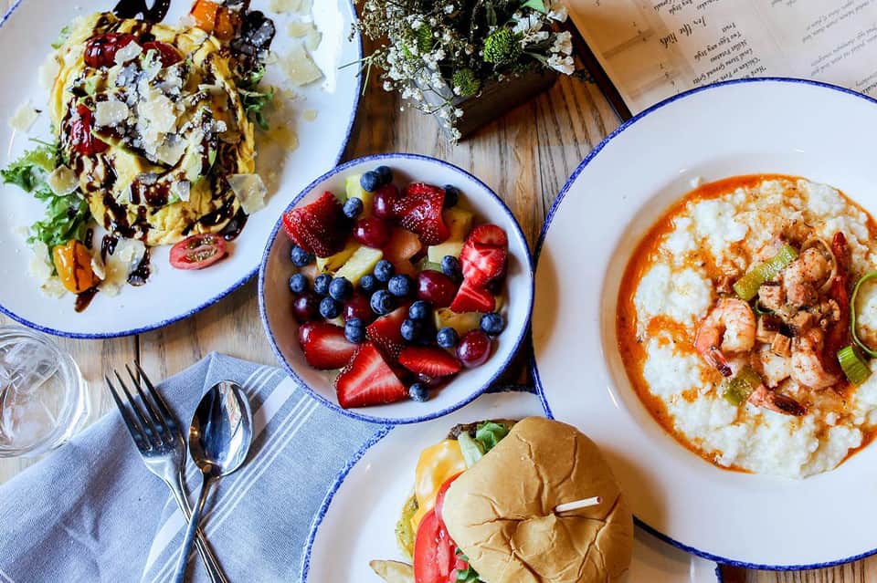 Overhead view of breakfast dishes including omelets, fruit bowl, and seafood pasta