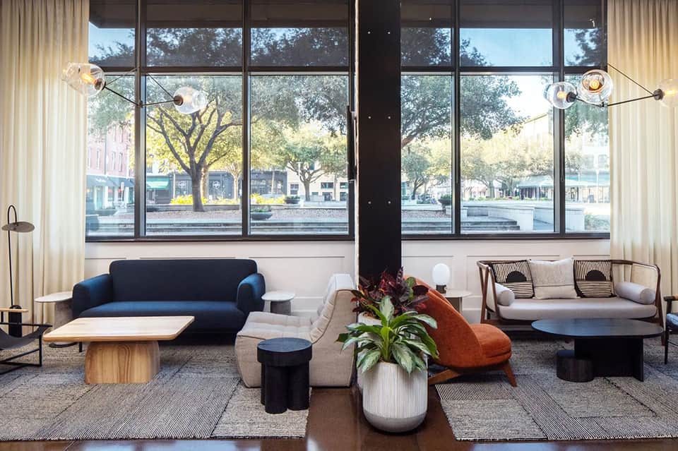 Modern hotel lobby lounge with floor-to-ceiling windows, contemporary furniture, and natural light