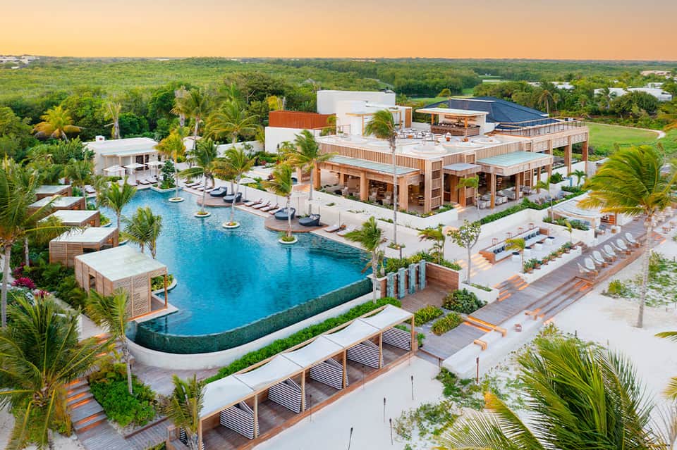 Aerial view of luxury resort with lagoon-shaped pool, palm landscaping, and lush grounds