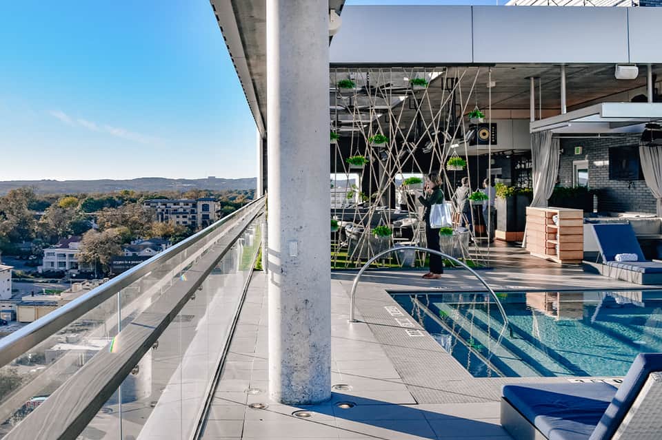 Modern rooftop pool deck with city views, hanging plants, infinity pool, and contemporary design elements