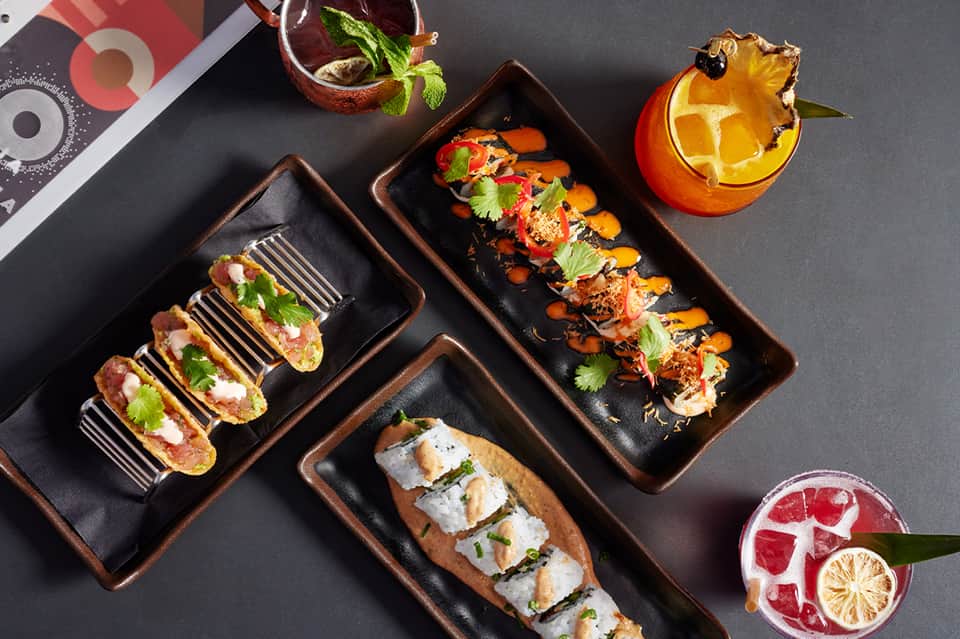 Upscale restaurant appetizers on black plates with craft cocktails