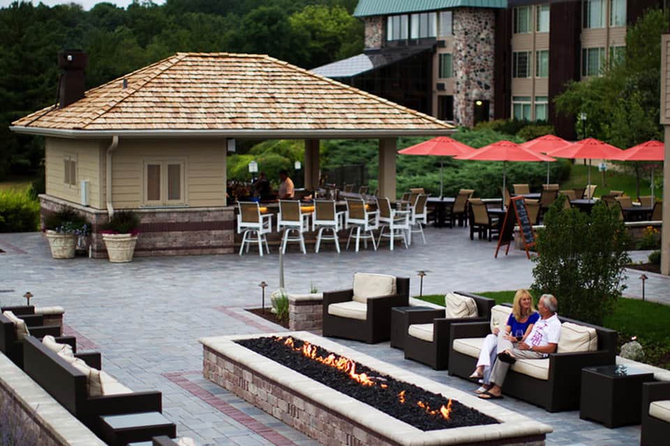 Resort courtyard with firepit, lounge seating, red umbrellas, and gazebo pavilion