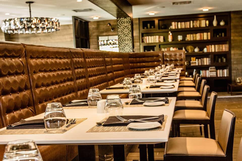 Upscale private dining room with brown leather banquette seating and formal place settings