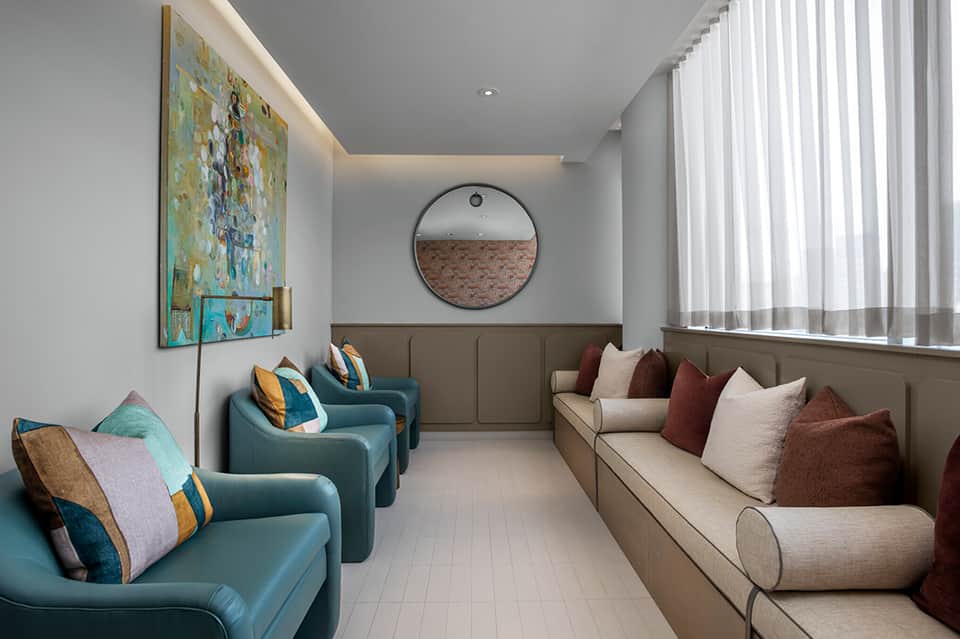 Modern spa lounge with teal armchairs, neutral sofa, and minimalist contemporary design