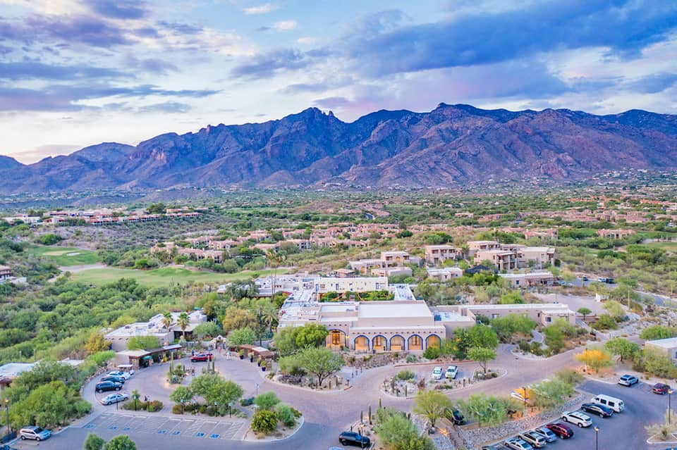 Desert resort exterior with Southwestern architecture, mountains, parking area, and desert landscaping