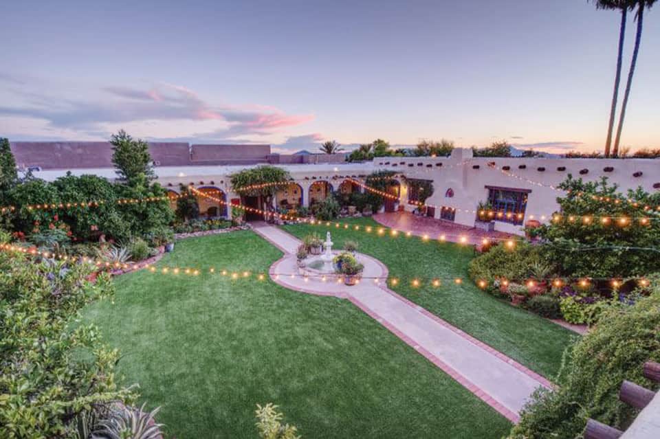 Waterfront garden terrace with illuminated archways, manicured lawn, and water views at twilight