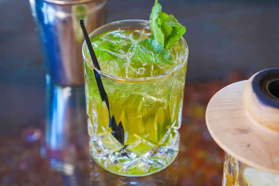Refreshing mojito cocktail with mint and lime garnish, cold glass with ice and black straw