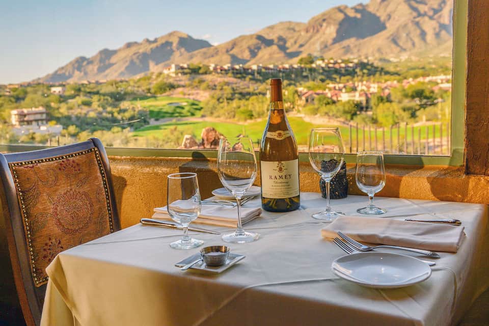 Fine dining table setting with wine bottle, glasses overlooking desert mountain valley