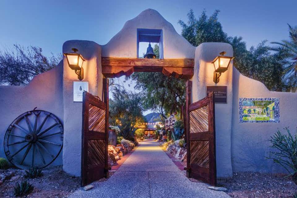 Southwestern-style resort entrance gate at twilight with decorative lanterns and mountain views