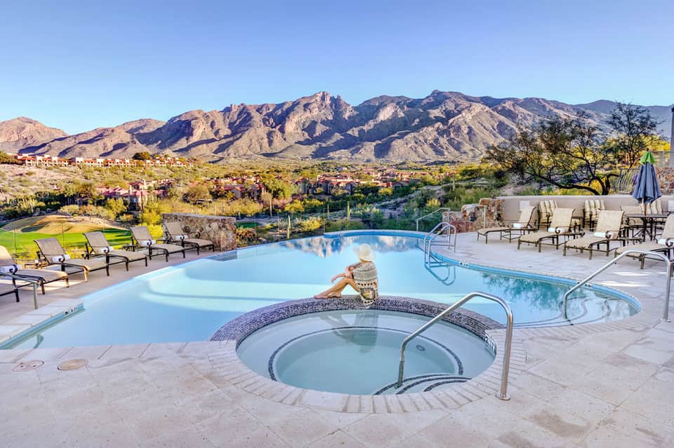 Resort pool and hot tub with desert mountain backdrop and lounge seating.