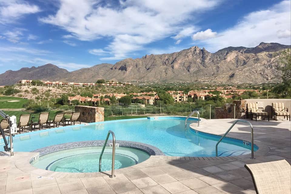 Resort pool and hot tub with mountain views, lounge chairs, and desert landscape