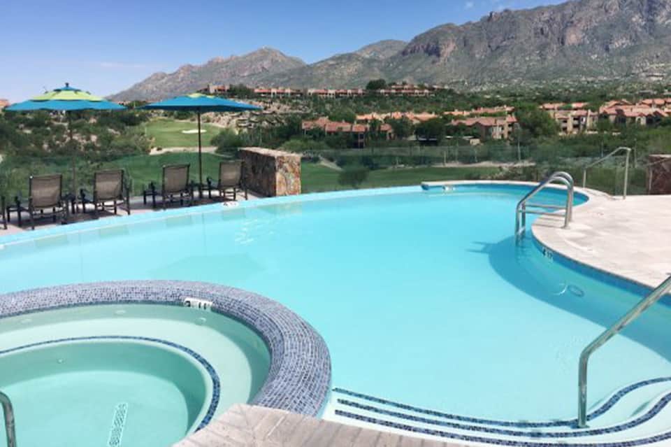 Resort pool with spa tub against mountain backdrop, lounge chairs, and desert landscape