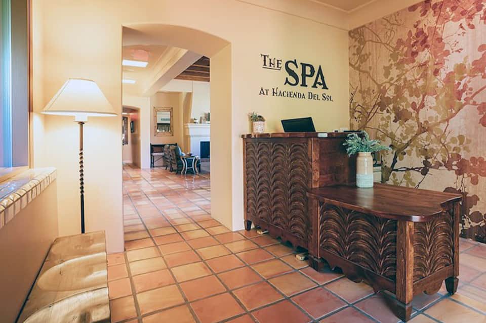 Spa entrance with decorative wooden desk, botanical wall art, and warm terracotta tile flooring