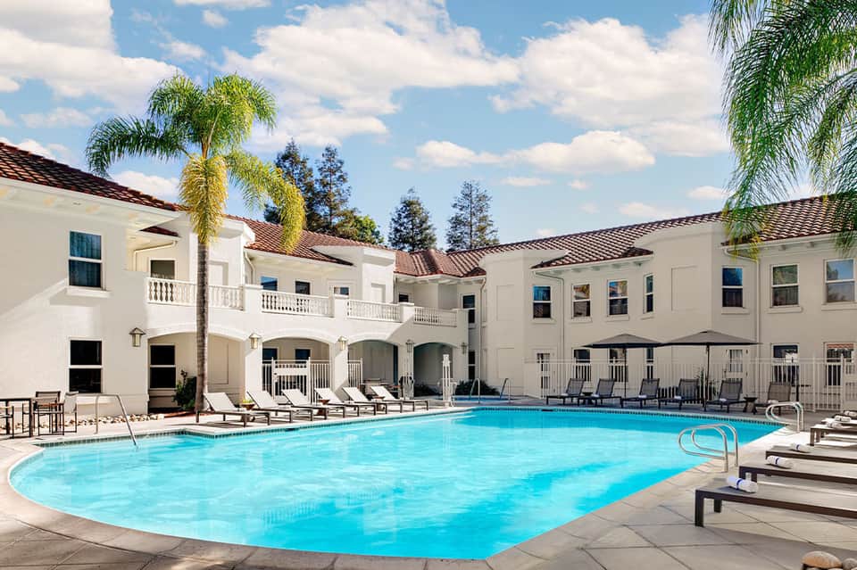 Resort courtyard pool with white Spanish colonial architecture and palm trees