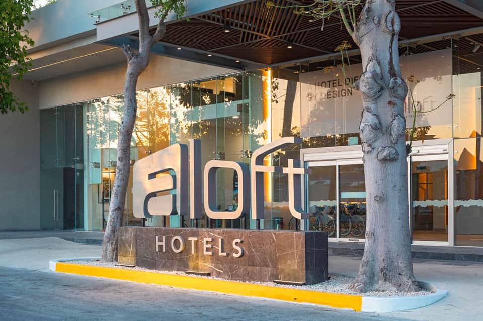 Aloft Hotels storefront entrance with modern signage and glass facade at dusk