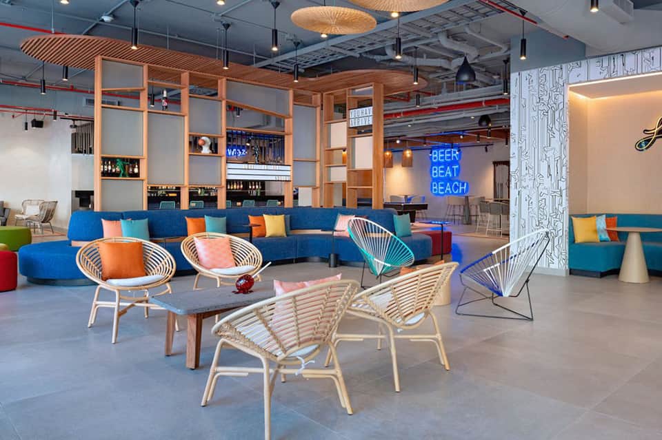 Modern resort lounge with colorful seating, neon signage, and tropical decor
