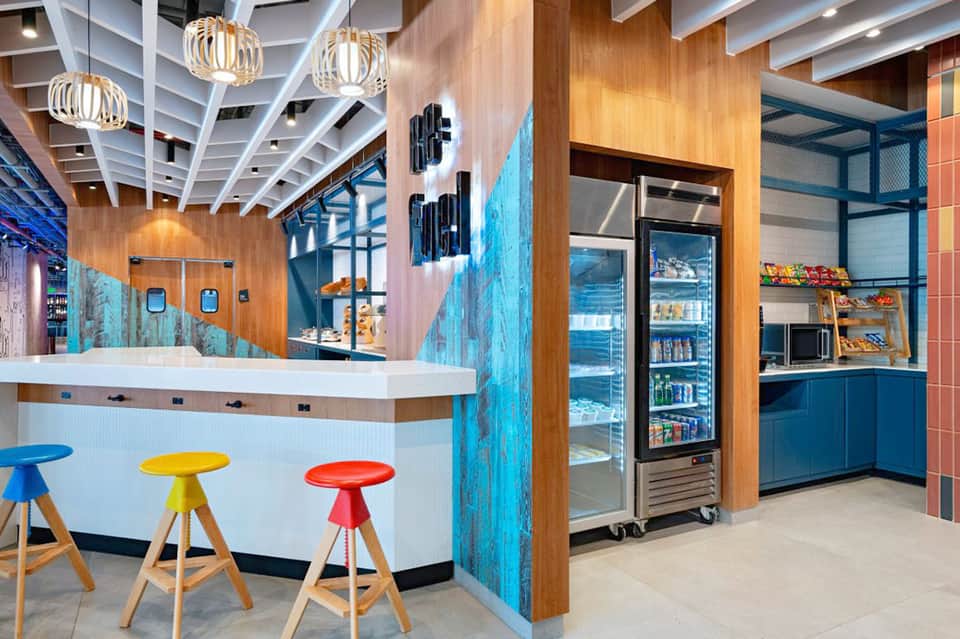 Contemporary hotel snack bar with colorful stools, wood accents, and ocean-themed decor