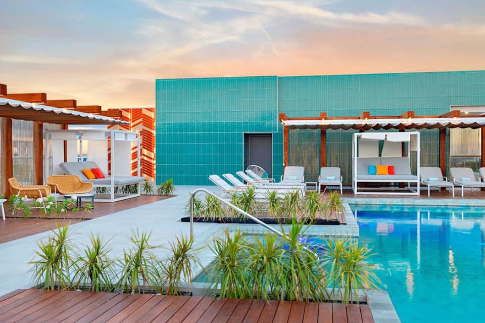 Modern resort pool with turquoise water, cabanas, and architectural canopies