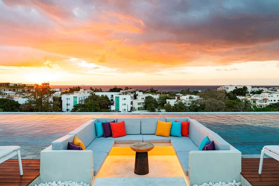 Sunset view from an elevated platform with colorful cushioned seating and coastal homes
