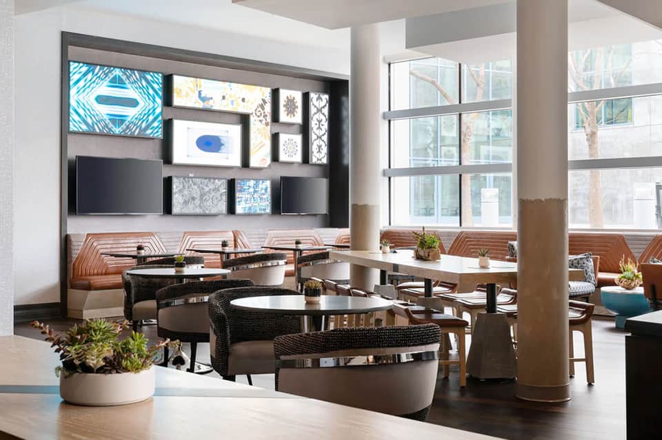 Contemporary hotel lounge with media wall, curved seating, and floor-to-ceiling windows