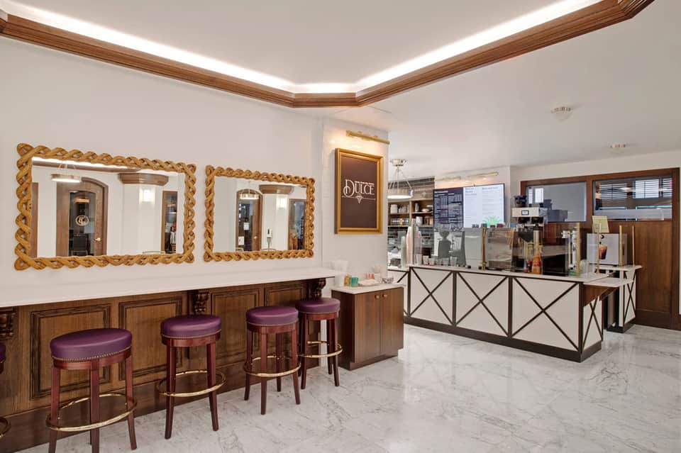 Upscale salon interior with ornate mirrors, purple stools, and polished reception desk