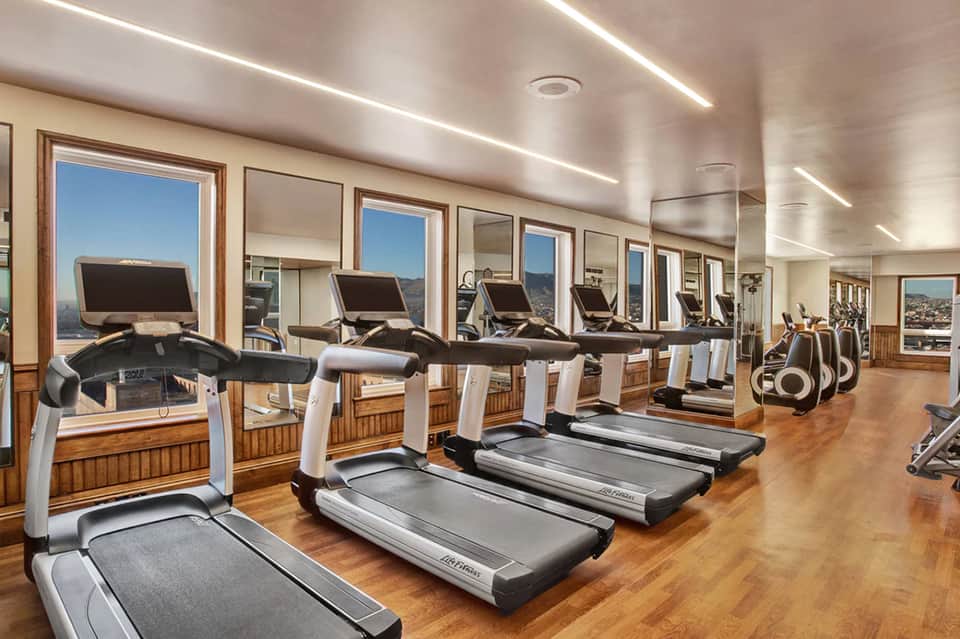 Modern hotel fitness center with treadmills and equipment facing floor-to-ceiling windows