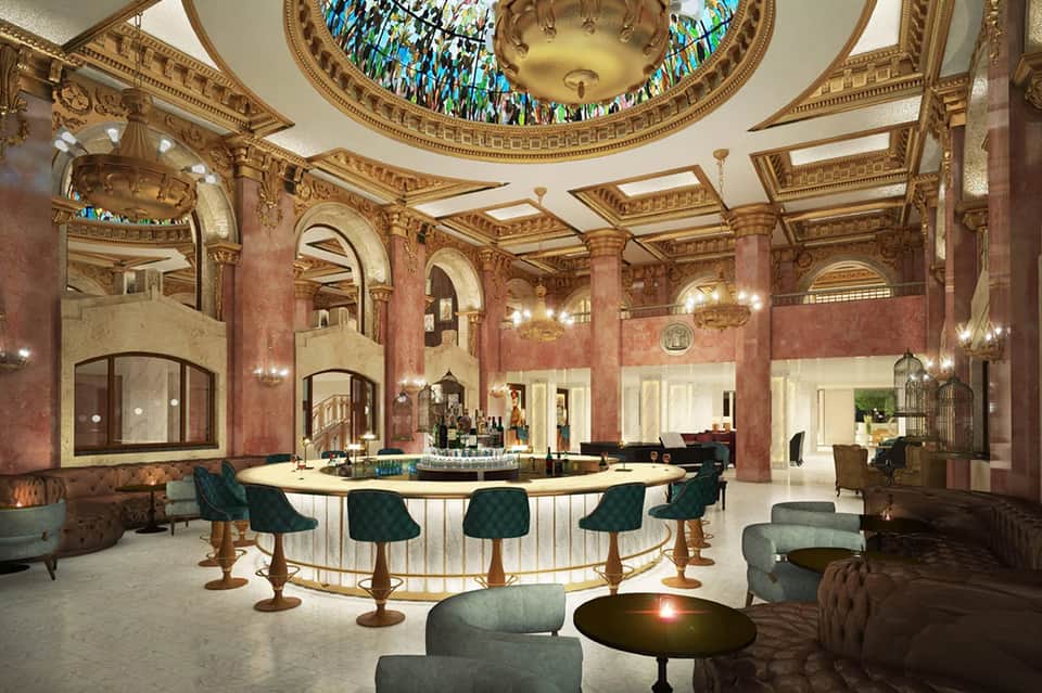 Ornate hotel lobby with pink marble columns, decorative ceiling, and circular bar counter