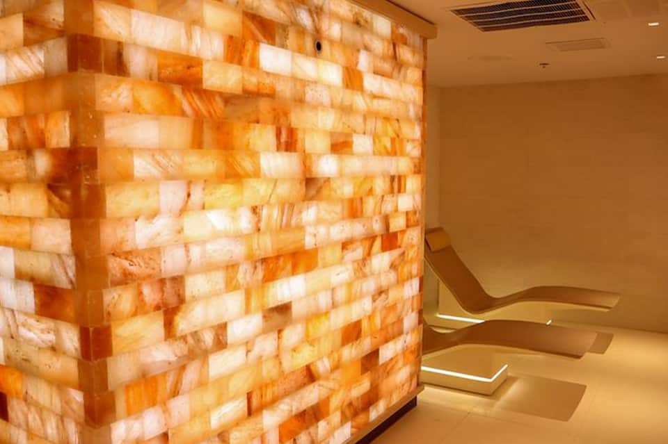 Modern spa interior with glowing Himalayan salt brick wall and curved seating benches