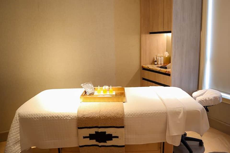 Spa treatment room with massage bed, candles, and minimalist wellness décor