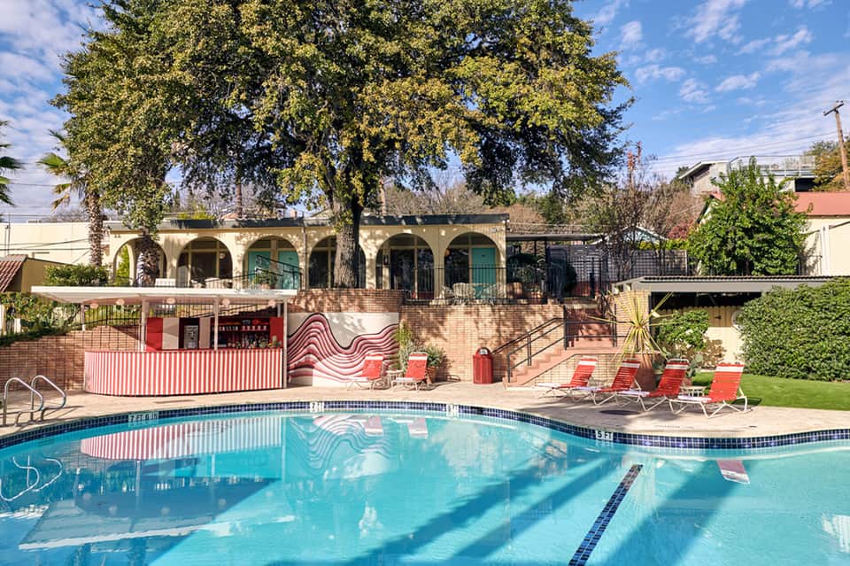 Swimming pool with retro red and white design elements and tropical landscaping