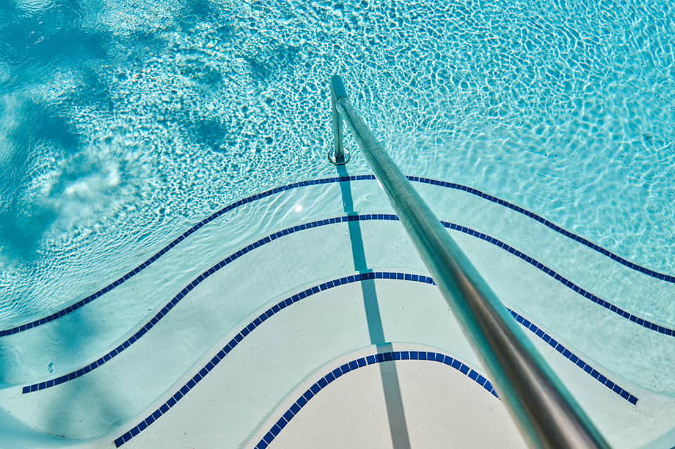 Swimming pool lane from above showing lane dividers, water texture, and pool starting block