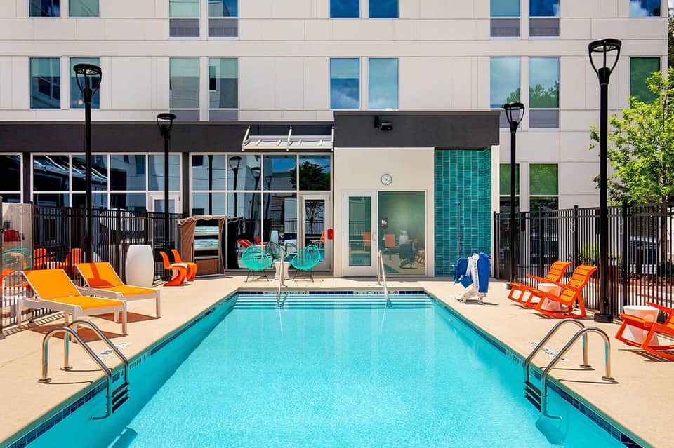 Contemporary resort pool with orange loungers and modern building facade
