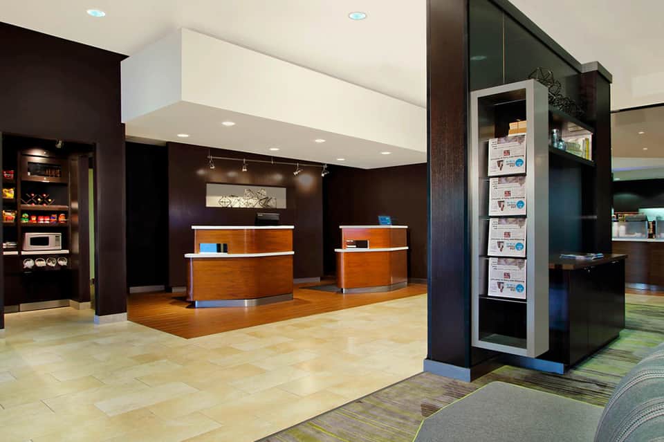 Modern hotel lobby with curved wooden reception desks and contemporary dark wood interior design