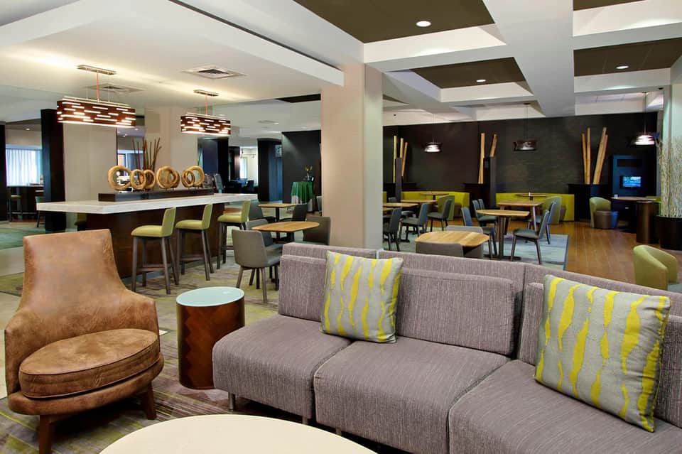 Modern hotel lobby with bar seating, gray sofa, and contemporary furnishings