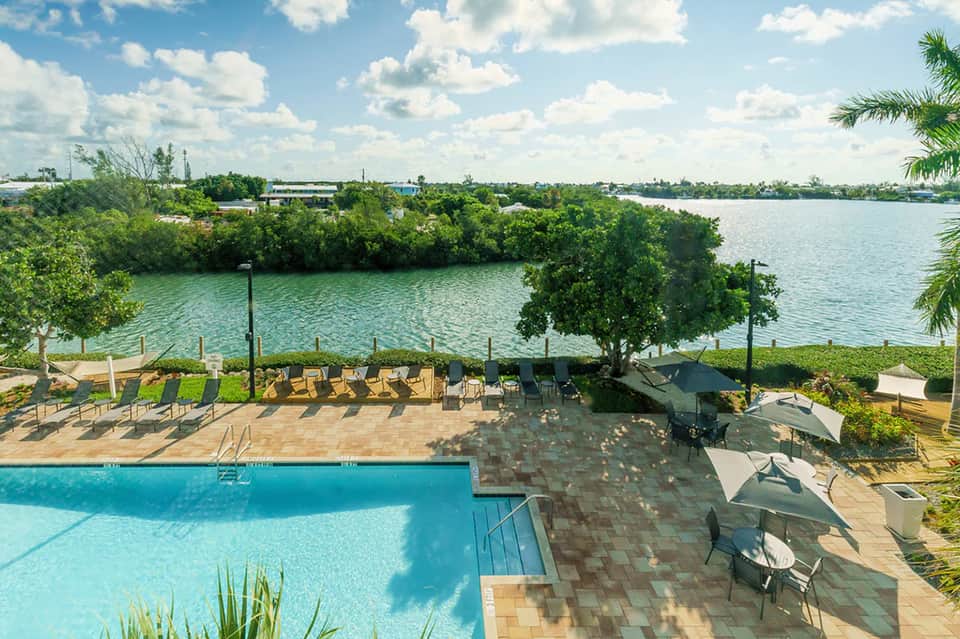 Waterfront resort pool with mangrove views, loungers, and boat dock access