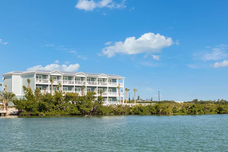 Waterfront hotel with white facade and palm trees along calm turquoise bay