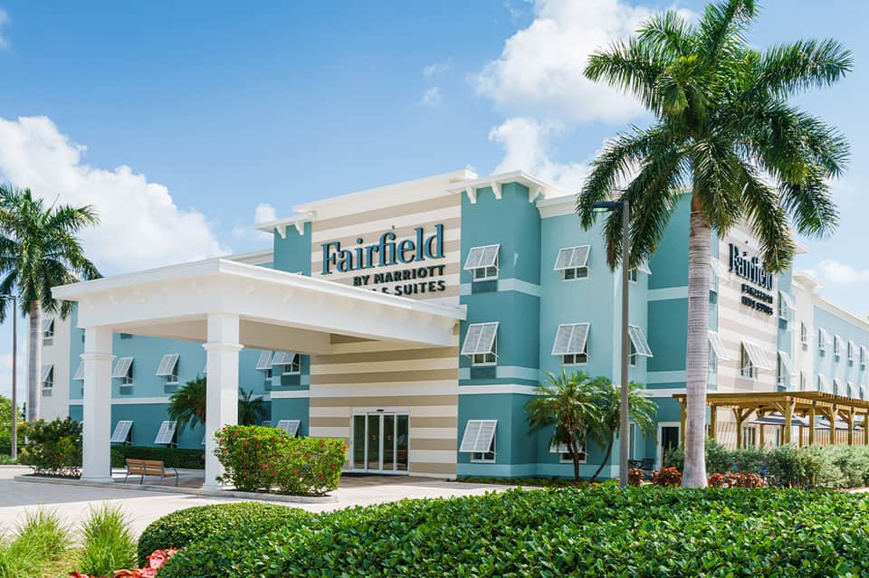 Fairfield by Marriott Suites hotel exterior with turquoise and white facade and palm trees