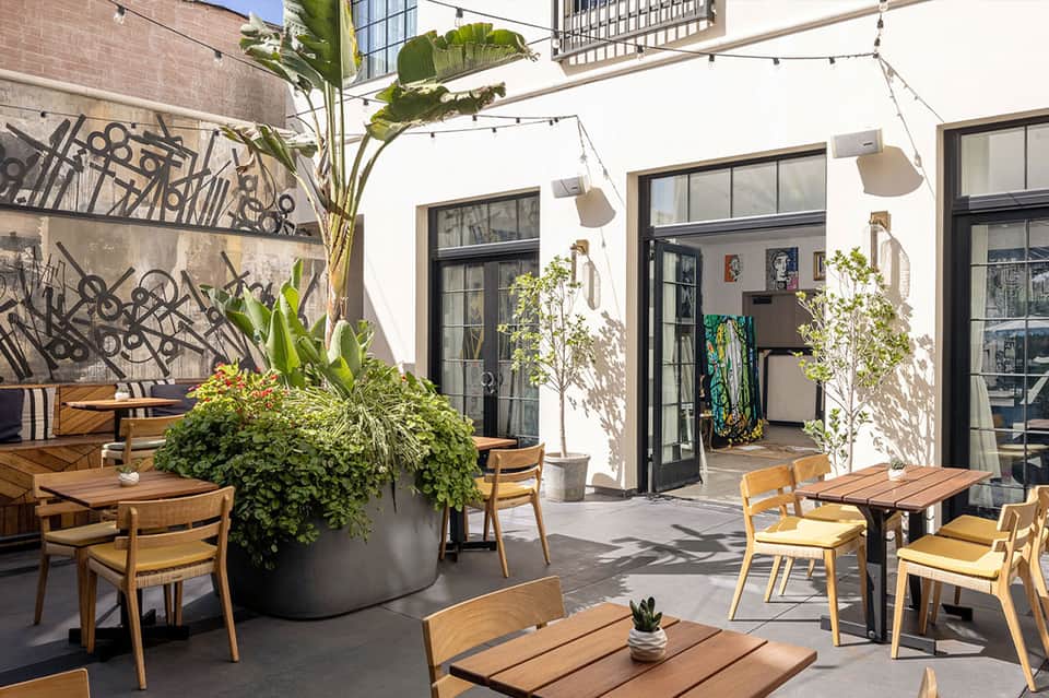 Modern outdoor terrace with wooden furniture, plants, and contemporary wall art