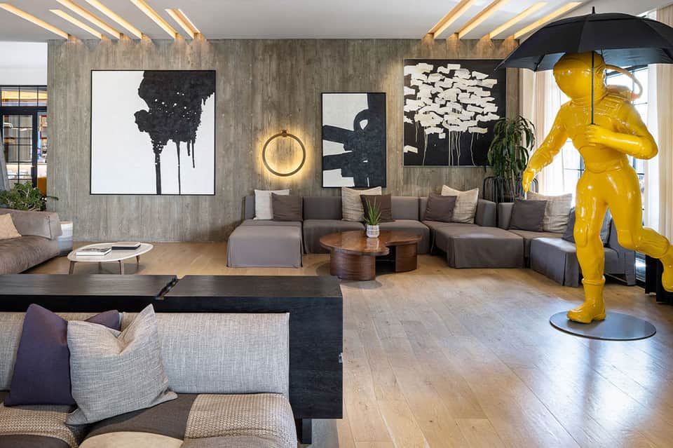 Modern hotel lobby with contemporary art, gray seating, and yellow sculpture