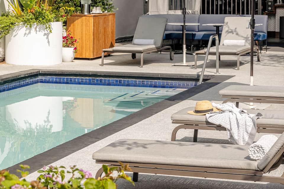 Modern resort pool area with lounge chairs, white planters, and manicured landscape