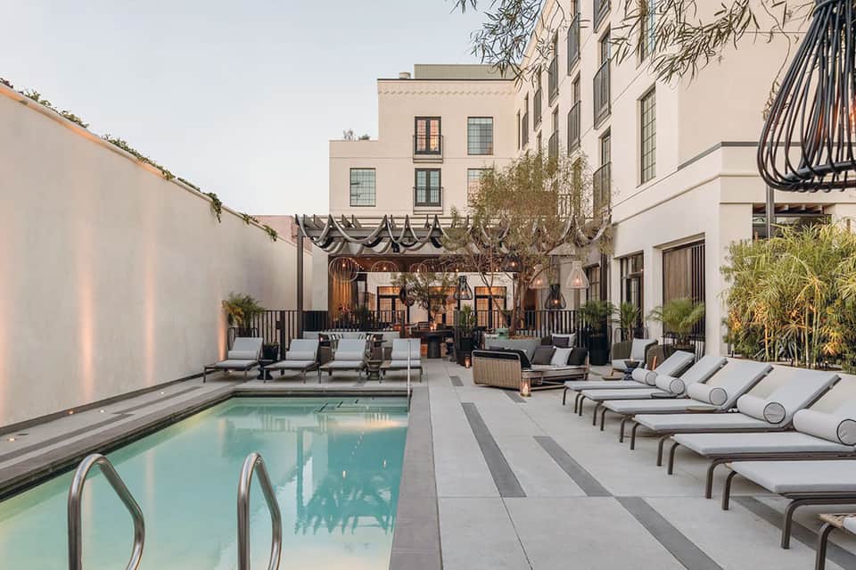 Urban courtyard pool with modern loungers, lounge seating, and architectural lighting at dusk