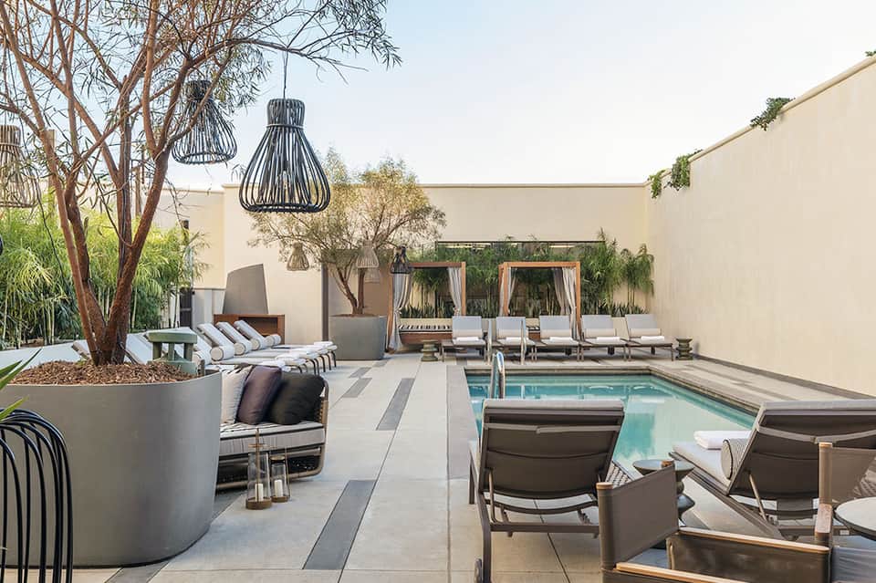 Contemporary courtyard pool area with fire pit, loungers, cabanas, and landscaping