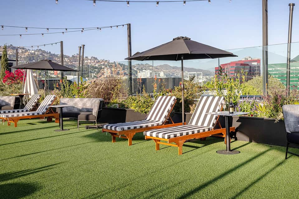 Rooftop lounge area with striped lounge chairs, black umbrellas, and cityscape views