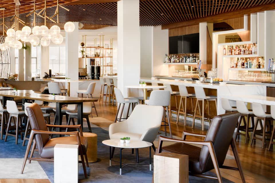 Elegant lounge with wooden ceiling, pendant lights, modern seating, and full bar area