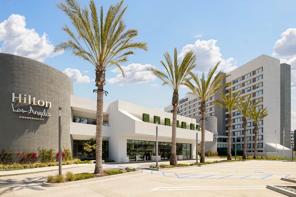 Modern Hilton hotel exterior with contemporary architecture, palm trees, and manicured landscaping