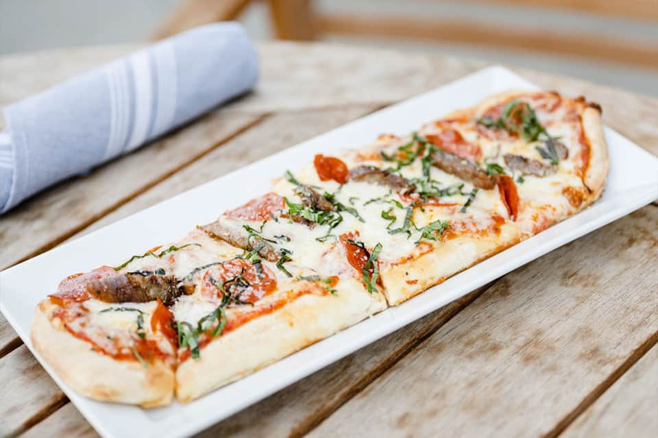 Gourmet flatbread pizza served on white plate at resort restaurant