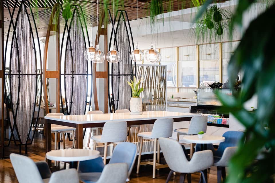 Modern restaurant interior with decorative black arch dividers, pendant lights, natural wood tables, and city views