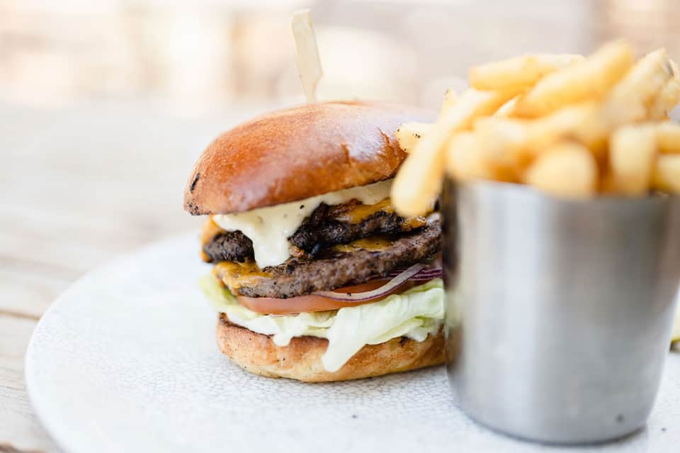Gourmet cheeseburger with fries on white plate at upscale restaurant