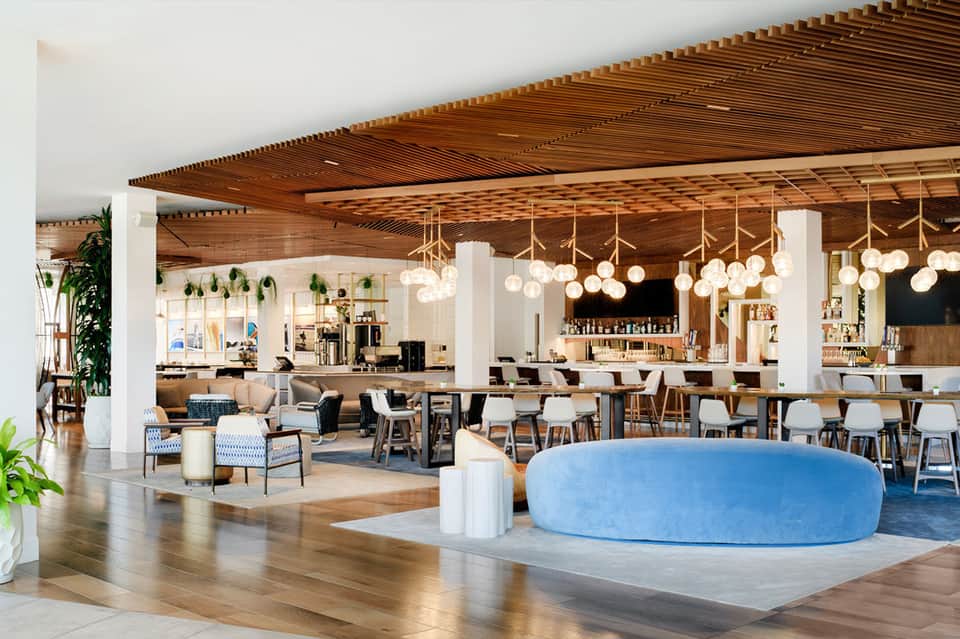 Modern hotel lobby lounge with wooden ceiling, pendant lights, bar, and seating areas