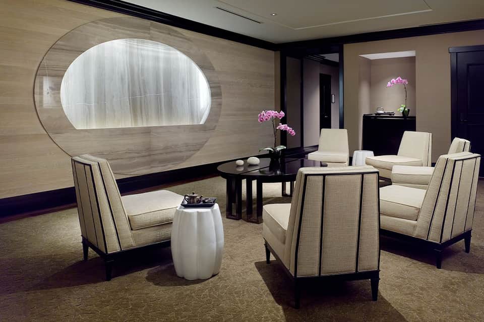 Luxurious spa lounge with cream chairs, illuminated wall art, and orchid flowers